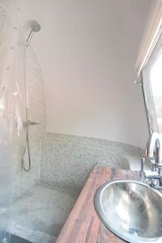 a bathroom with a sink, mirror and shower stall in the corner next to a window