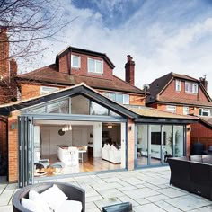 an outdoor living area with patio furniture and brick buildings in the background, surrounded by trees