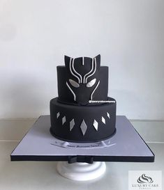 a black and white cake with silver designs on it's sides, sitting on top of a table