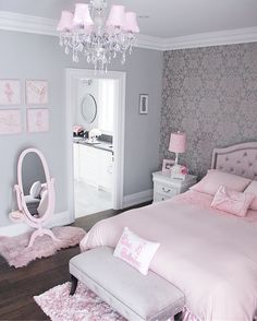 a bedroom decorated in pink and white with a chandelier