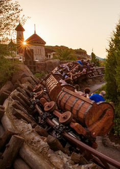 an amusement park with lots of wooden barrels and people on the ride at sunset or dawn