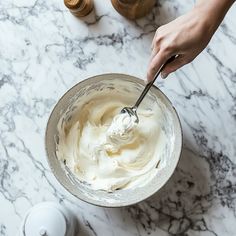 a person mixing cream in a bowl on a marble table