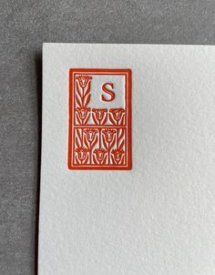 the letter s is made out of red and white paper with an orange stamp on it