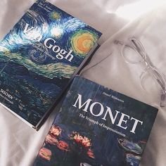 two books sitting on top of a bed next to each other near eyeglasses