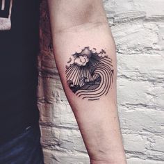 a man's arm with a wave and sun tattoo design on the left forearm