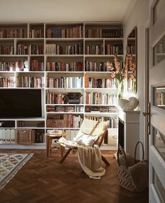 a living room filled with lots of books on top of a book shelf next to a tv