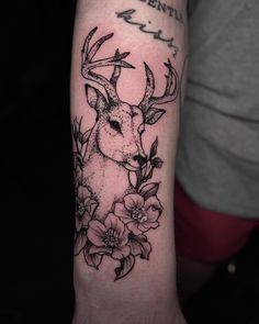 a deer with antlers and flowers on his arm