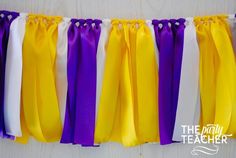 colorful streamers hanging from the side of a white wall with purple, yellow and white ribbons