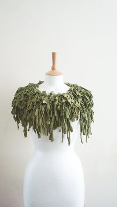 a white mannequin with some green leaves on it's neck and shoulders