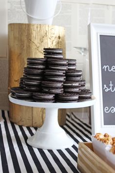 chocolate covered donuts are stacked on a cake stand with a chalkboard sign in the background