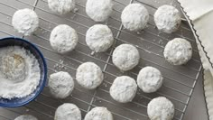 several balls of powdered sugar next to a blue bowl on a wire cooling rack