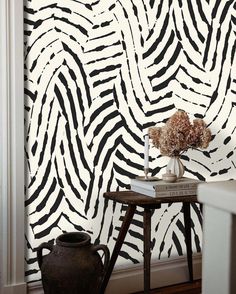 a vase with flowers sitting on top of a table in front of a zebra print wall