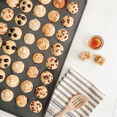 a pan filled with muffins next to a cup of tea