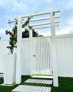 a white fence with a planter and some flowers in it on the grass outside