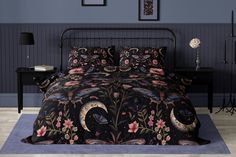 a bed with a black and pink comforter on top of it next to a night stand