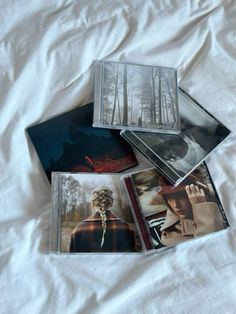 four polaroid photos are laying on top of a white sheet, with trees in the background