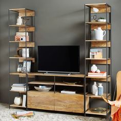 an entertainment center with shelves and a flat screen tv on it's stand in front of a gray wall