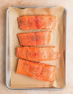 four salmon fillets on a baking sheet ready to go into the oven for cooking