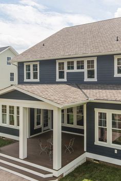 a blue house with white trim on the front porch and covered patio area, surrounded by lush green grass