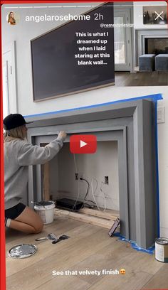 a woman kneeling down to paint a fireplace