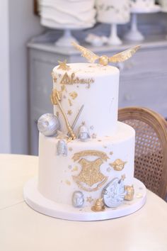 a three tiered white cake with gold decorations