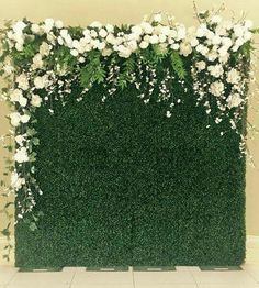 an artificial green wall with white flowers and greenery