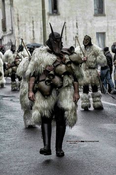 a man dressed in costume walking down the street with other men behind him wearing costumes