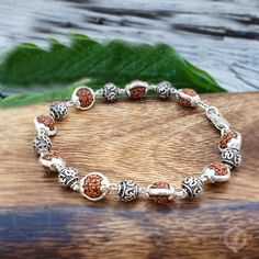 🌿 Welcome to a world of tranquility and spiritual connection with our stunning Five Face Rudraksha Beads Silver Capped (925 Sterling Silver) Bracelet, featuring serene Om charm delicately nestled between each bead! 🕉️✨ Crafted with care and precision, this bracelet embodies the perfect balance of elegance and spiritual significance. Each Rudraksha bead, adorned with durable sterling silver caps, symbolizes harmony, protection, and inner peace. 📿💖 💫 But this bracelet offers more than just ae Fusion Style Bracelets For Rituals And Festivals, Spiritual Sterling Silver Bracelets With Silver Clasp, Silver Beaded Bracelets With 8mm Beads For Meditation, Bohemian Sterling Silver Bracelet For Festivals, Spiritual Healing Bracelets For Festivals, Silver Beaded Bracelets For Meditation, Bohemian Sterling Silver Bracelets For Festivals, Silver Rosary Bracelet With Round Beads For Meditation, Adjustable Fusion Bracelets For Meditation