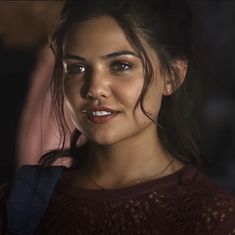 a close up of a person wearing a red shirt and holding a cell phone in her hand