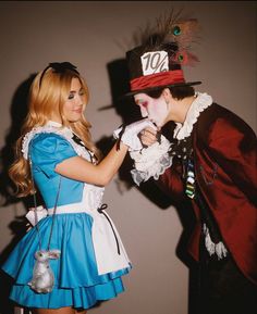 two people dressed up as alice and the mad hatter, one in blue dress