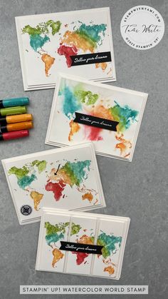 four watercolor world map cards with markers on the front and back, all in different colors