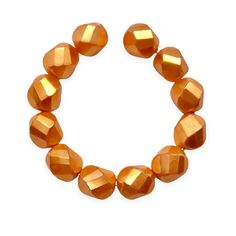 an orange bracelet with gold beads on a white background and one bead is in the shape of a heart