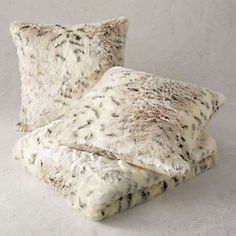 two pillows on top of each other in front of a white wall with black spots