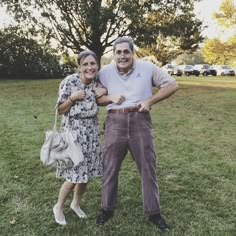 an older man and woman standing in the grass