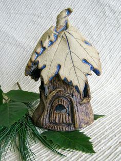 a small bird house sitting on top of a green leaf