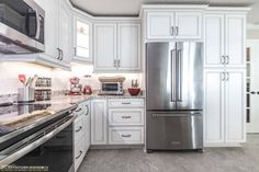 a kitchen with white cabinets and stainless steel appliances, including a silver refrigerator freezer