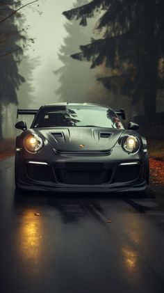 a black sports car driving on a wet road in the foggy forest at night