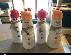 three snowmen made out of plastic bottles sitting on top of a counter