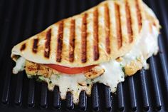 a grilled sandwich with tomatoes and cheese on it sitting on top of a grill