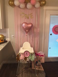 a baby's first birthday party with pink and gold decorations, balloons and presents