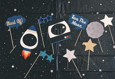 space themed photo booth props with stars, moon and rocket in the sky on a black background