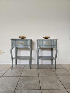 two blue tables with bowls on them against a white wall