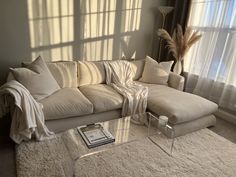 a living room with a couch, coffee table and large windows in the back ground