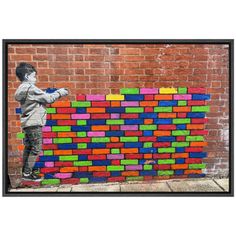 a man standing next to a wall made out of colored blocks with graffiti on it