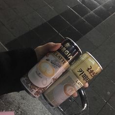 two cans of coffee being held by someone's hand