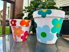 two painted flower pots sitting on top of a table