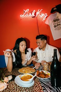 a man and woman sitting at a table with food