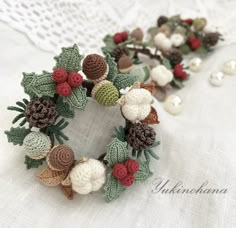 a crocheted wreath with pine cones, berries and acorns on it