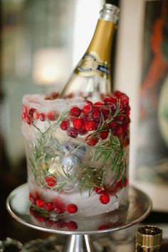 a bottle of champagne is sitting on top of a cake with cranberries and rosemary