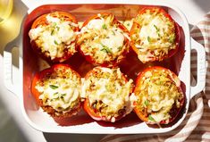 several stuffed tomatoes with cheese and herbs in a red casserole dish on a table